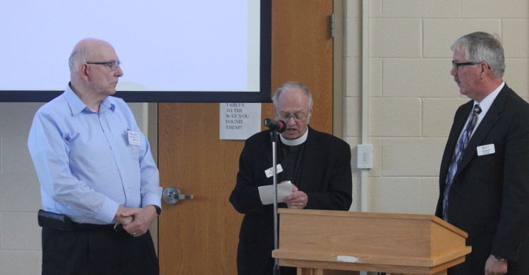 Michigan District president Chuck Bennett (right) and secretary Randy Larson (left) are installed by Michigan District pastoral advisor.